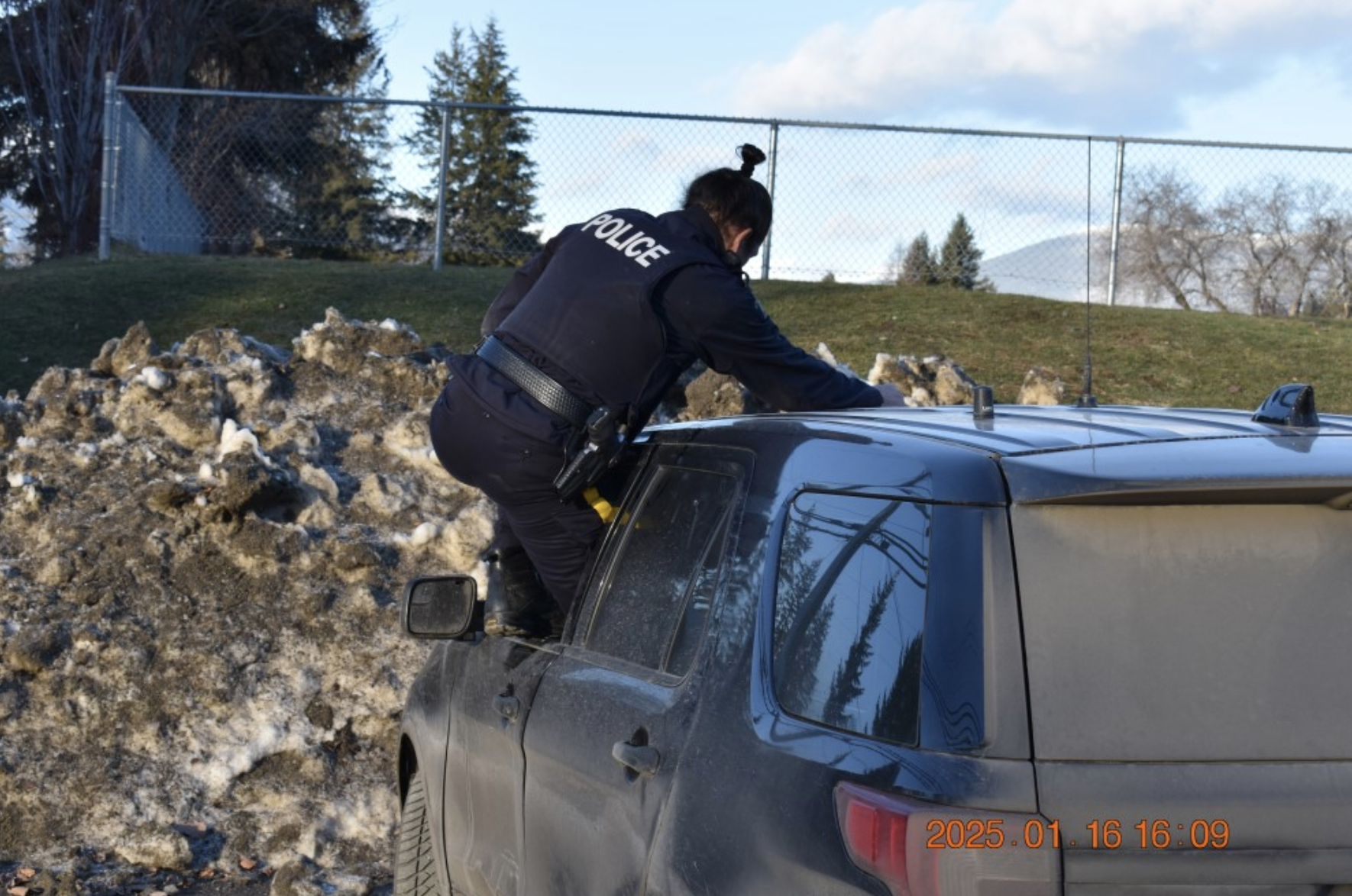 A BC Highway Patrol officer climbing out the window of a police SUV.
